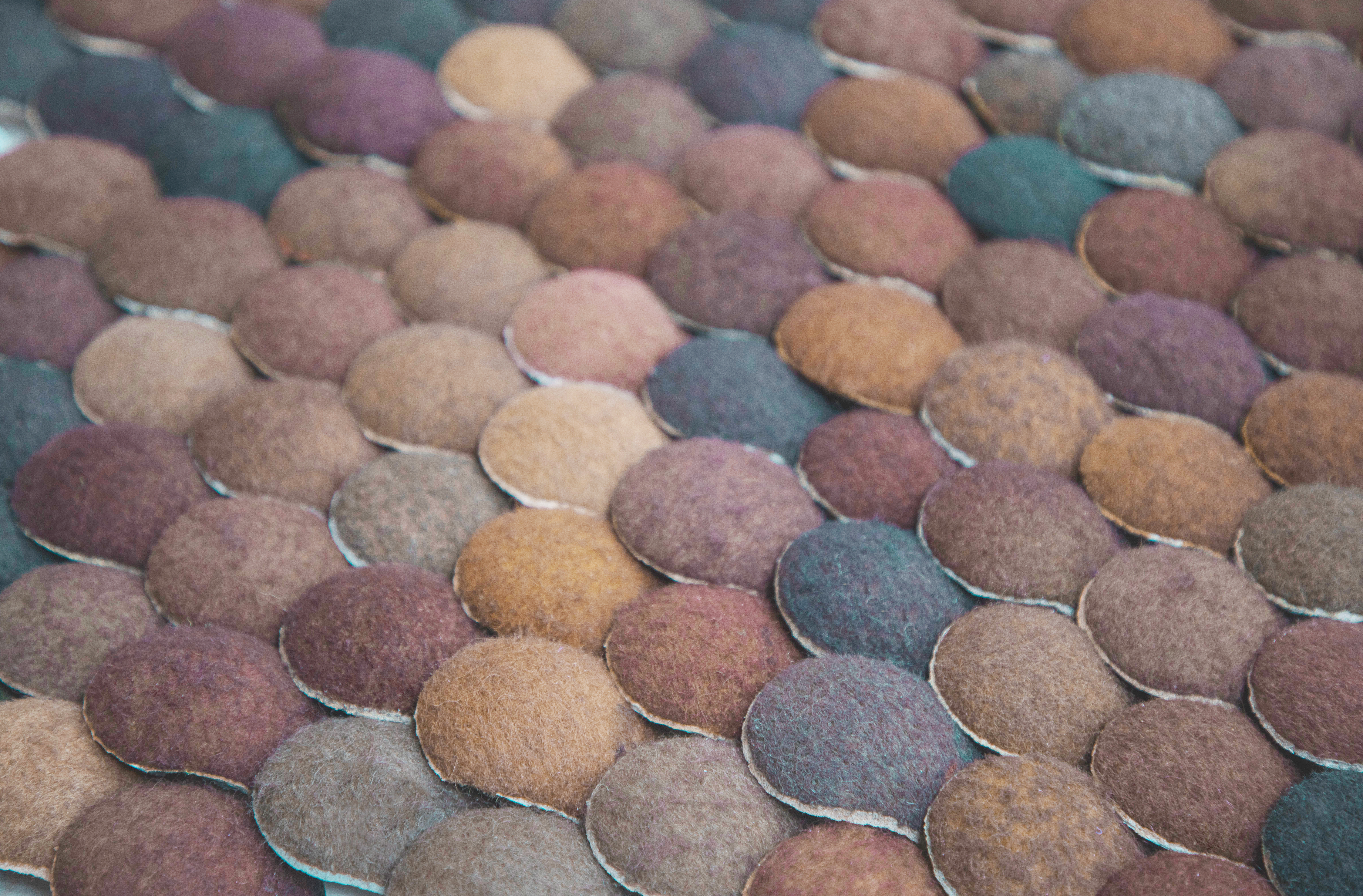 Consecutive circles of felt in muted colours layered in an overlapping pattern. 