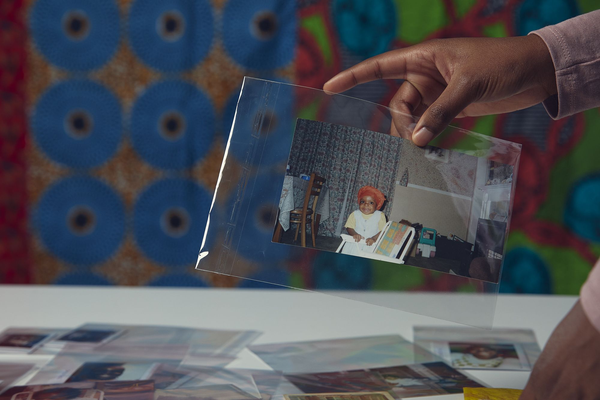 person holding up childhood photo in front of colourful background