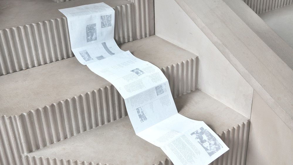 A long piece of paper drapes over a set of steps, folding at the edge of the steps. 