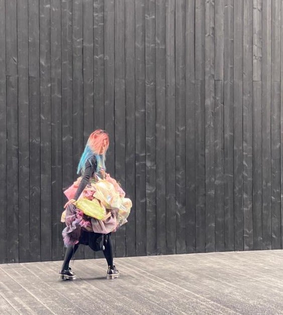 a woman modelling a colourful dress in a dark wooden room