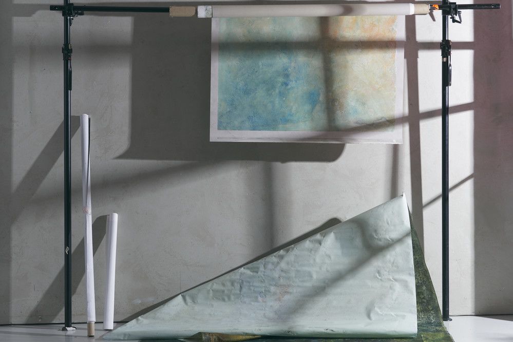 A grey walled studio with a roll of paper with a blue print on it