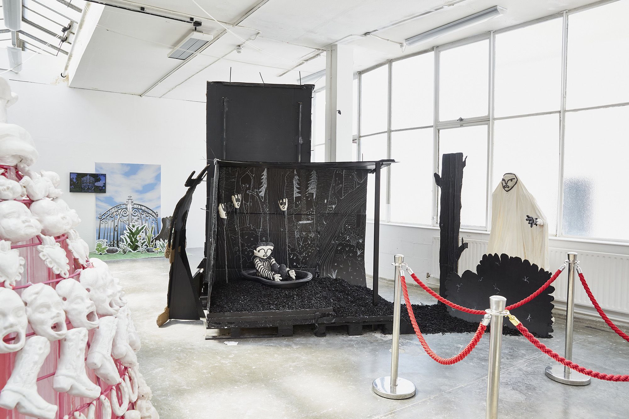A series of sculptures, including a black and white cardboard structure of a set, with a sculpture of young boy. Work is based on comic book drawings.  