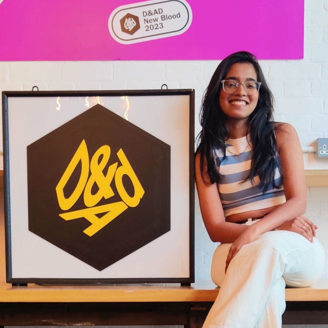 Student sat to the right of a framed logo of D&AD, the leading design and advertising charity