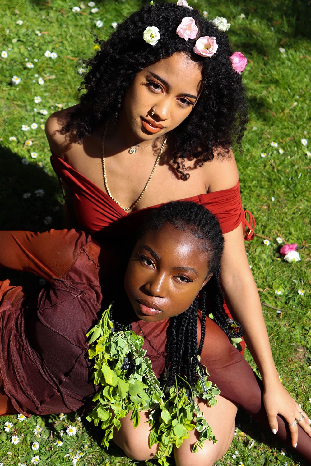 Photograph of two models surrounded by grass and flowers.