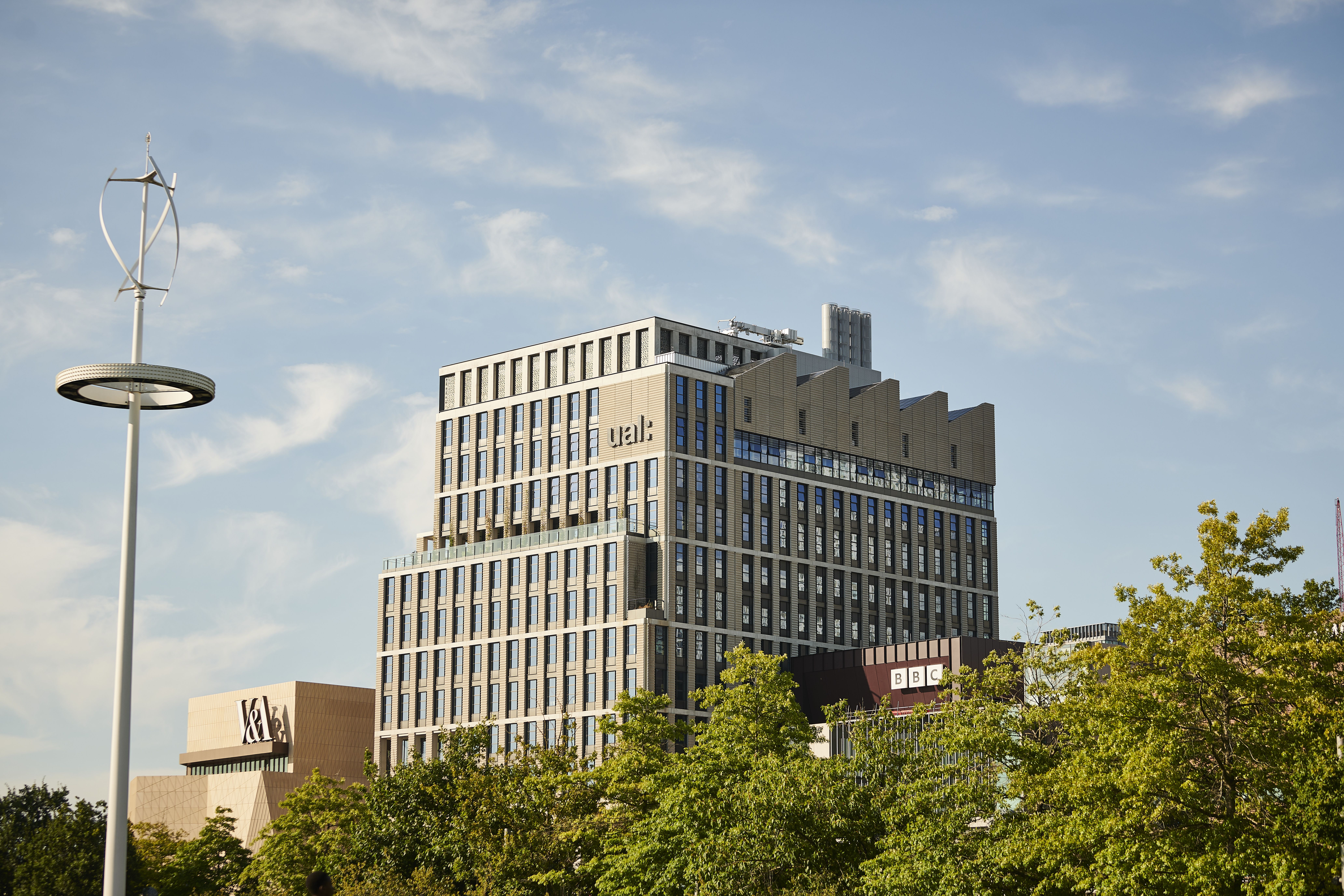 Large building pictured against blue skies and green trees.