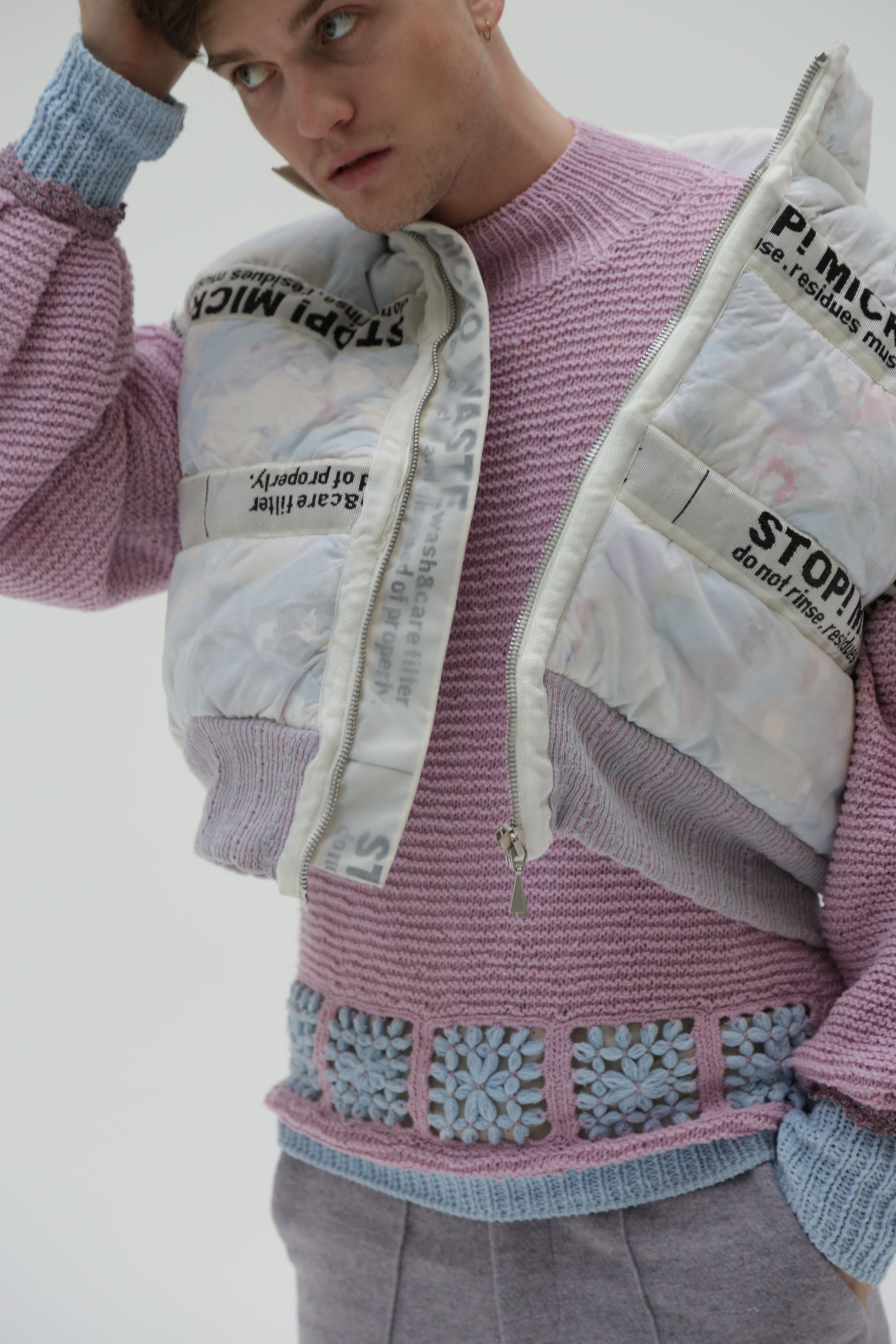 model in pink knitted jumper with blue embroidery, and multicoloured puffer jacket with text print