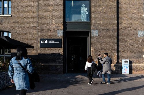 A close up of the entrance to the Central Saint Martins Granary building with people on their way inside and College branding visible