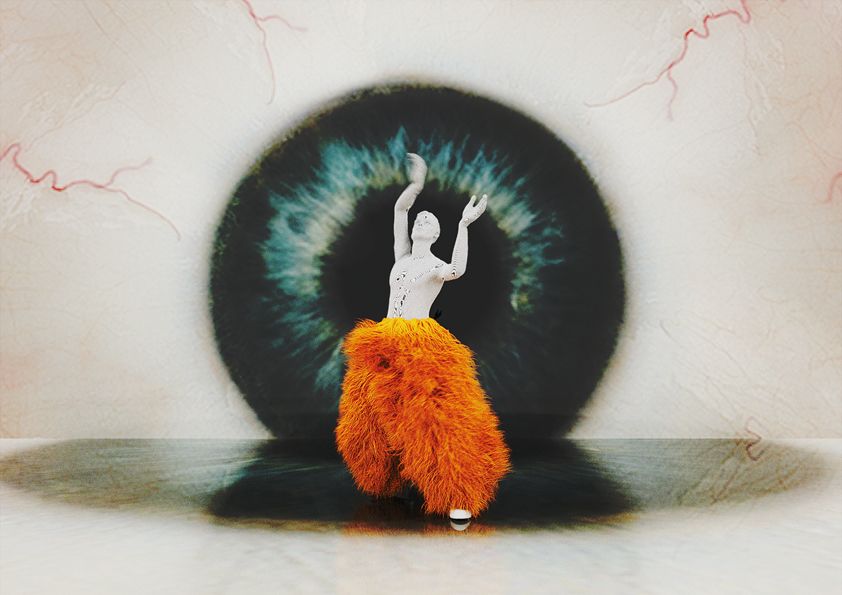 A mannequin with large orange fluffy trousers posing with the arms up in the air standing in front of a picture of a large eye ball.