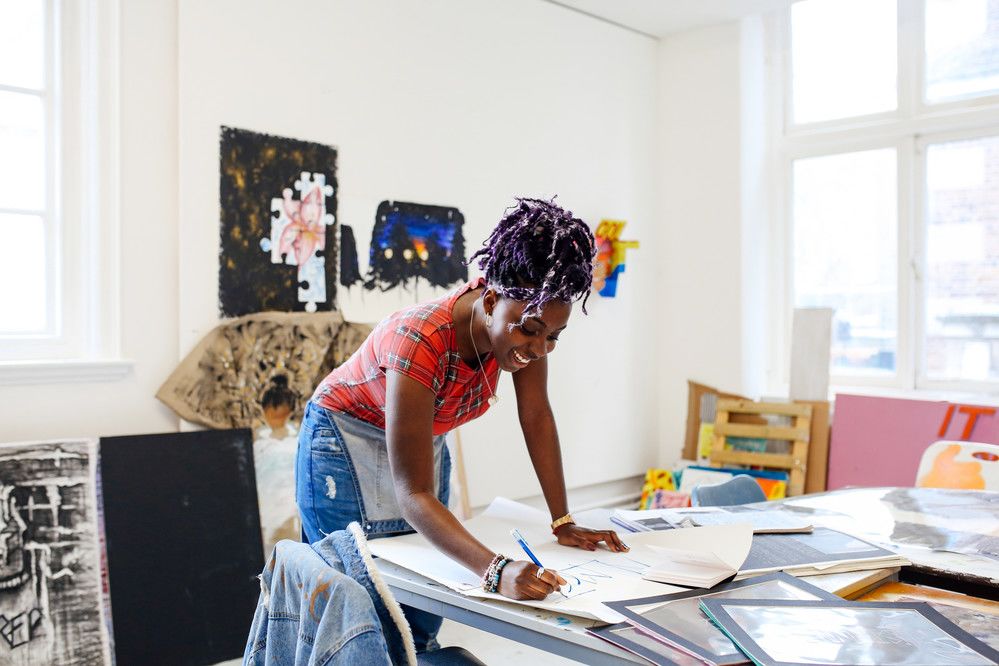 A person in an art studio drawing on paper on a table