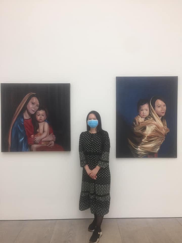a person wearing a face mask in between two paintings