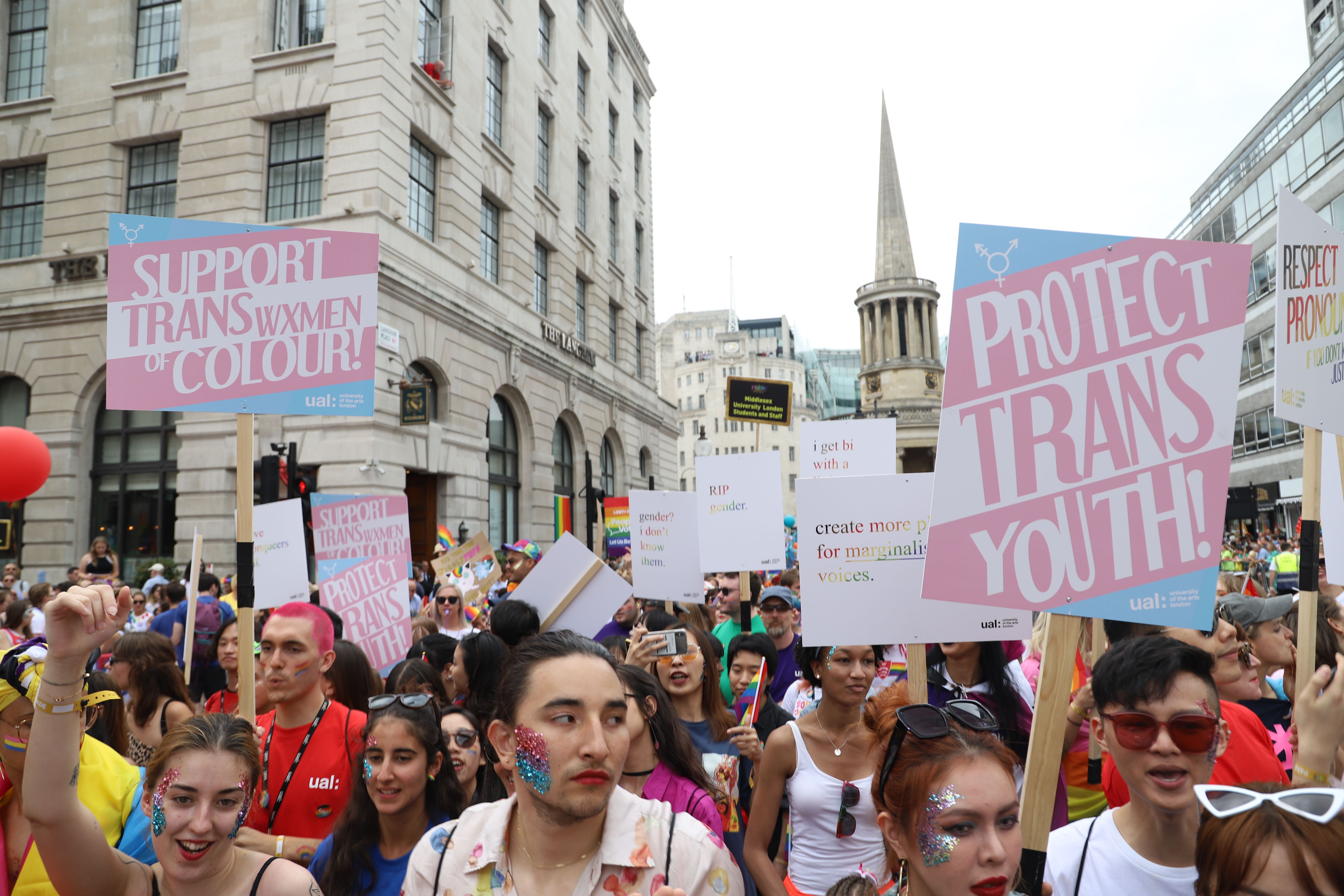 People marching in Pride, holding placards that say 'Protect Trans Youth'