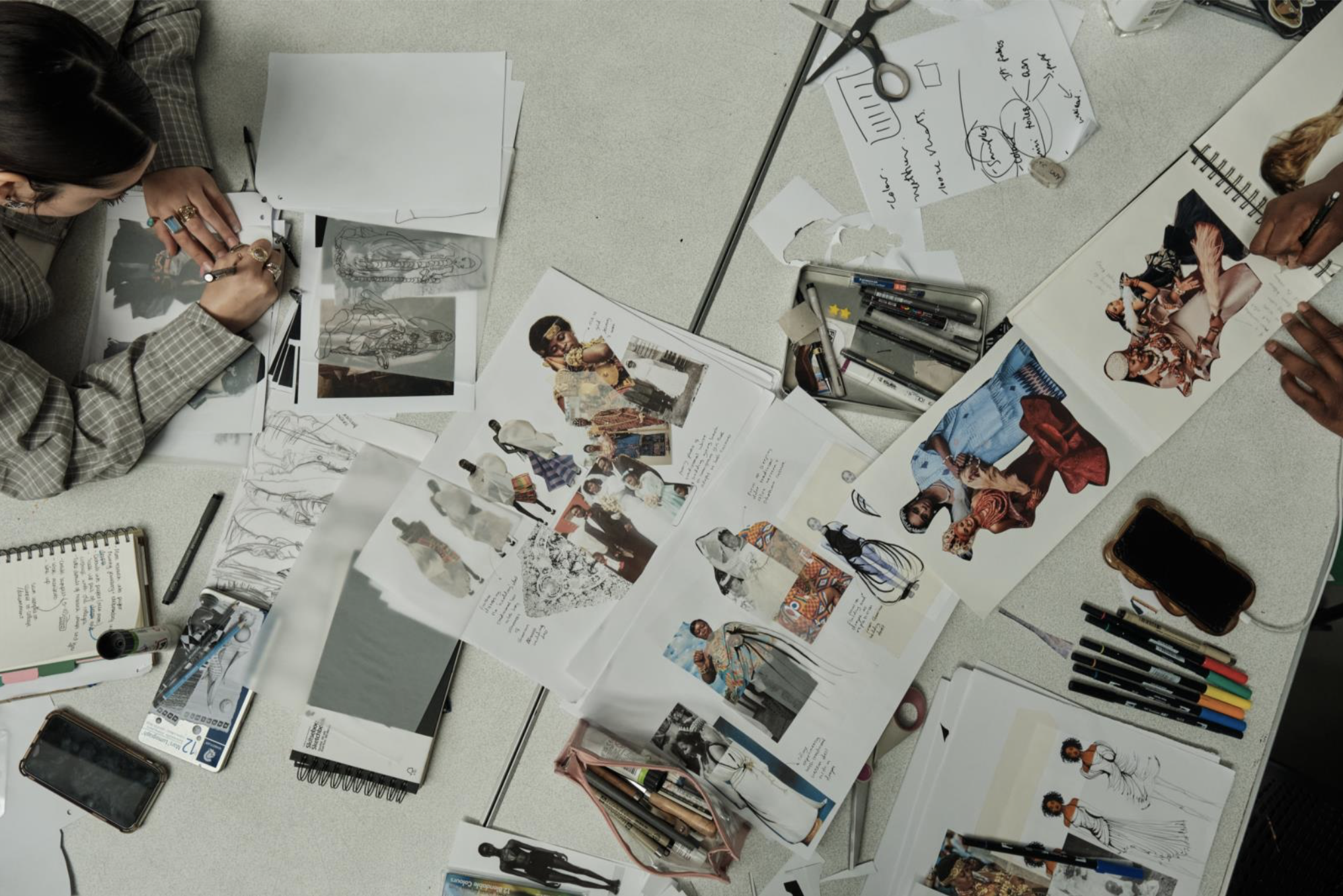 Ariel view shot of a student working on designs and a spread of papers across the table.