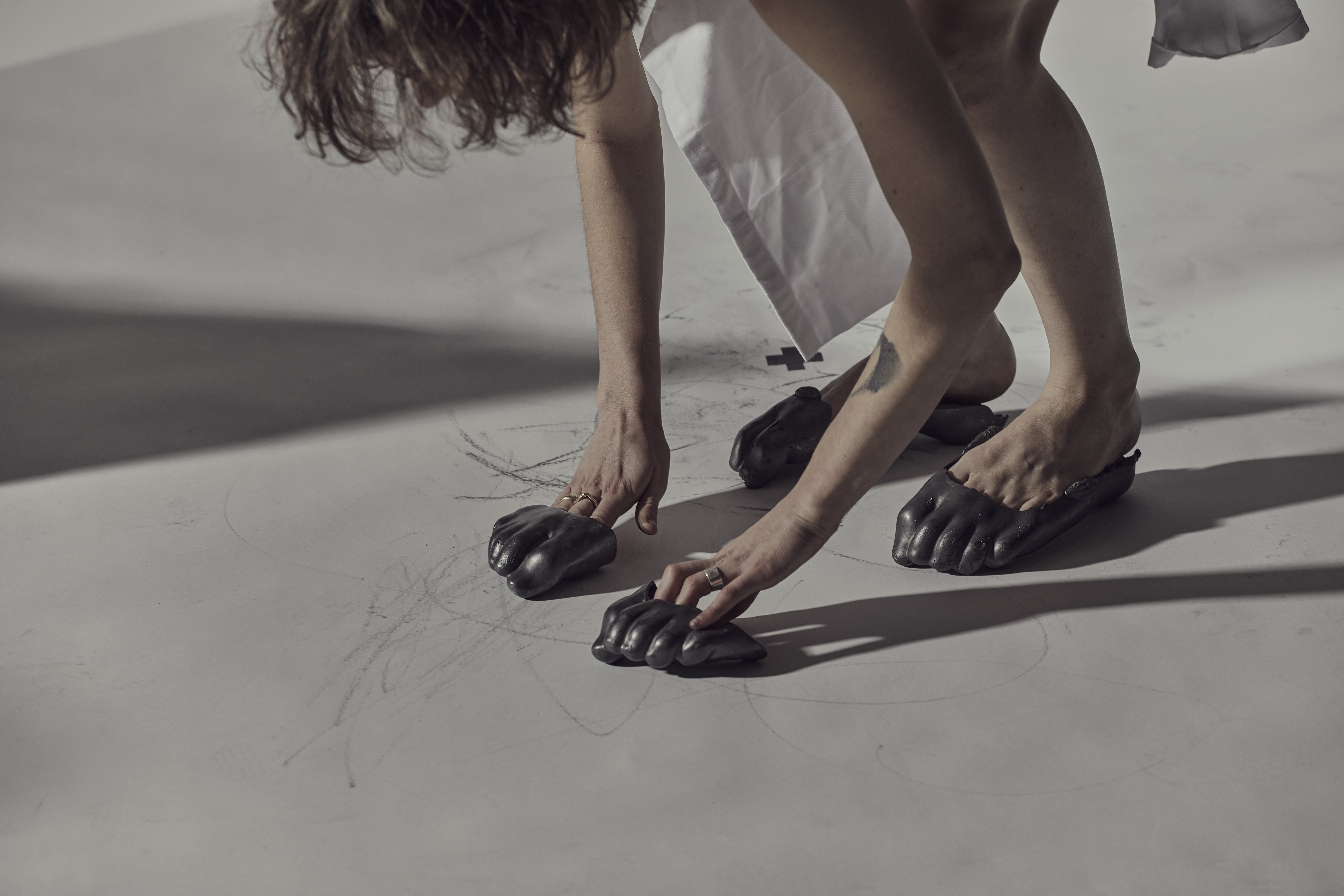 A person bending down using mould on their hands and feet to draw on the concrete ground.