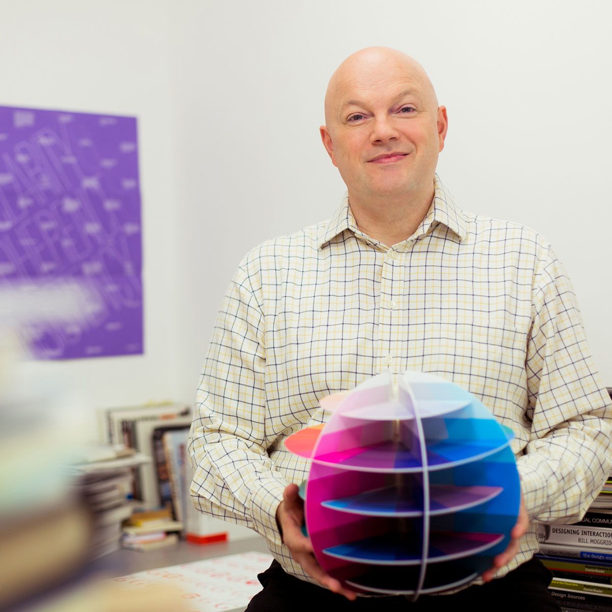 A man holds a brightly coloured paper globe.