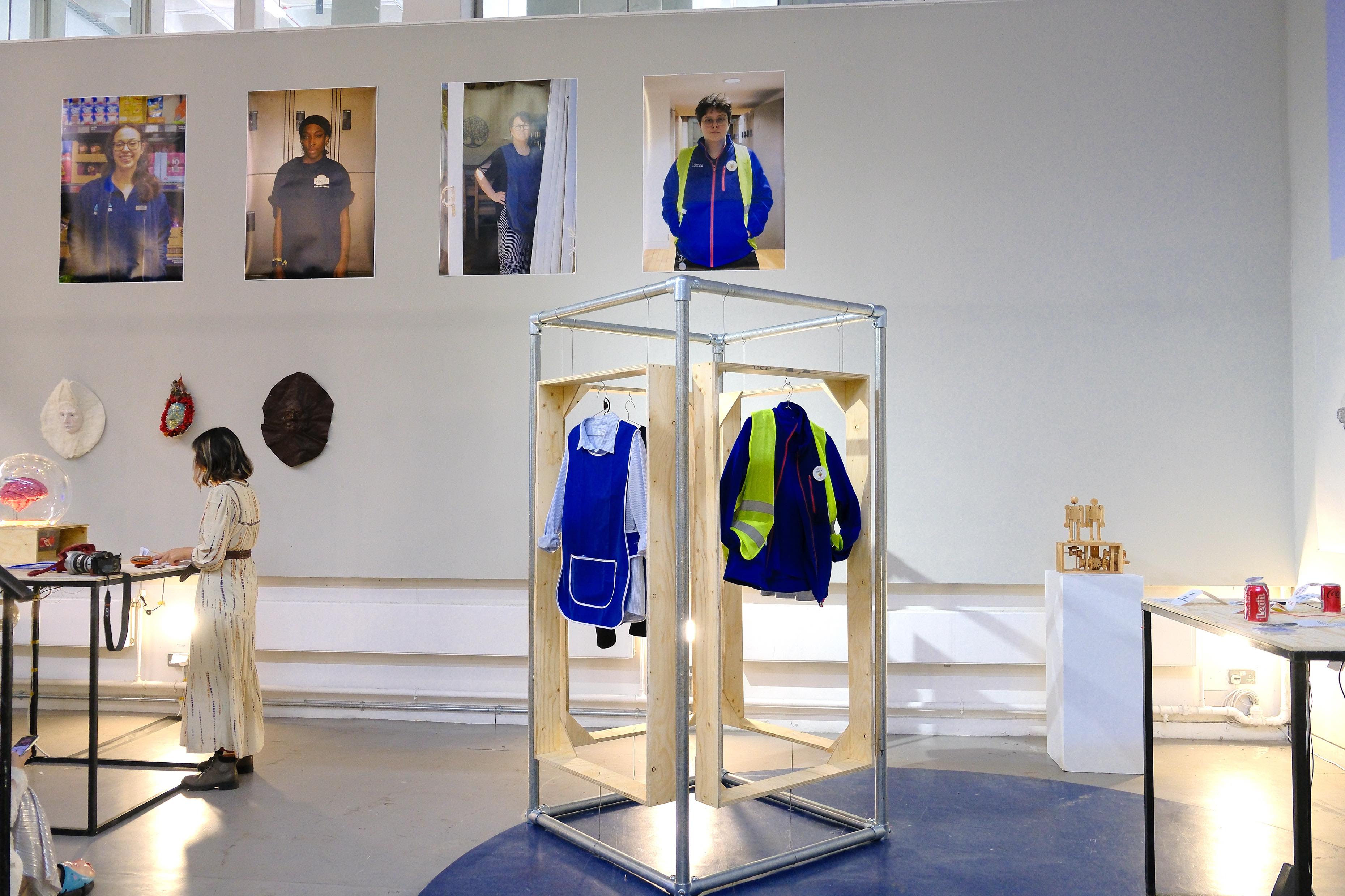 Exhibition showcase with clothes and attendants in the background. 