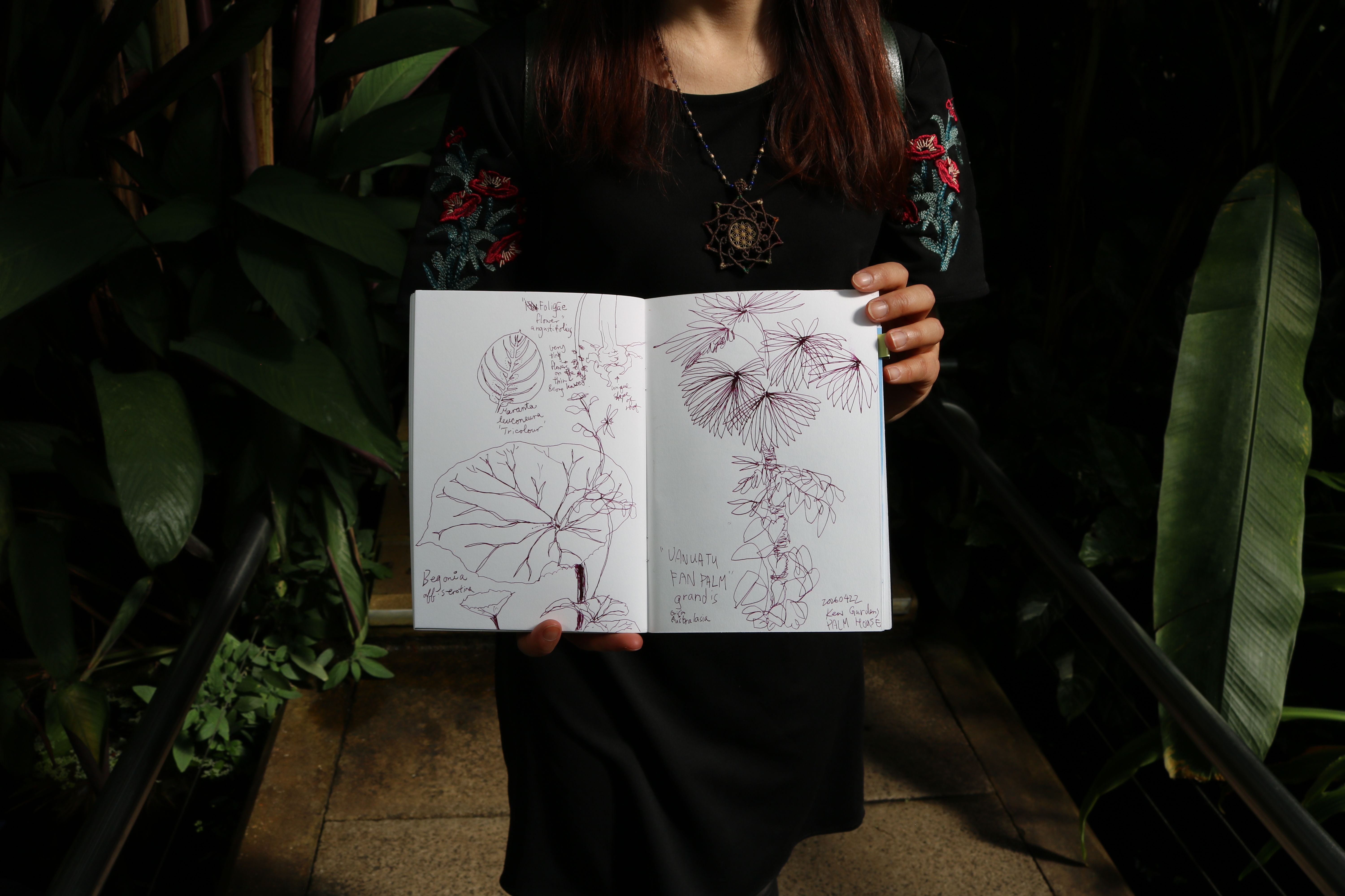 Someone holding a sketch book with drawings on them