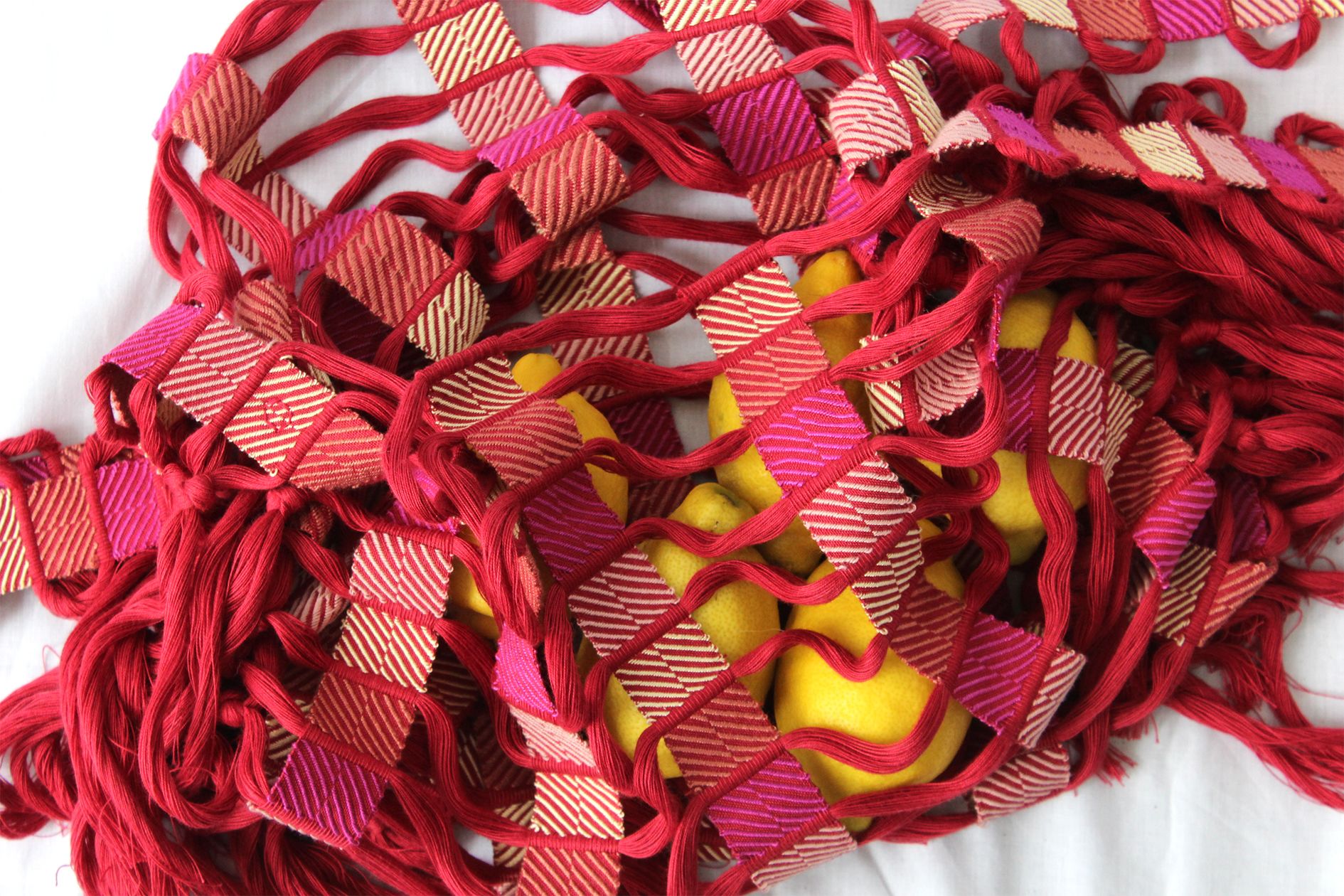 Lemons covered in strips of pink and red woven fabric 