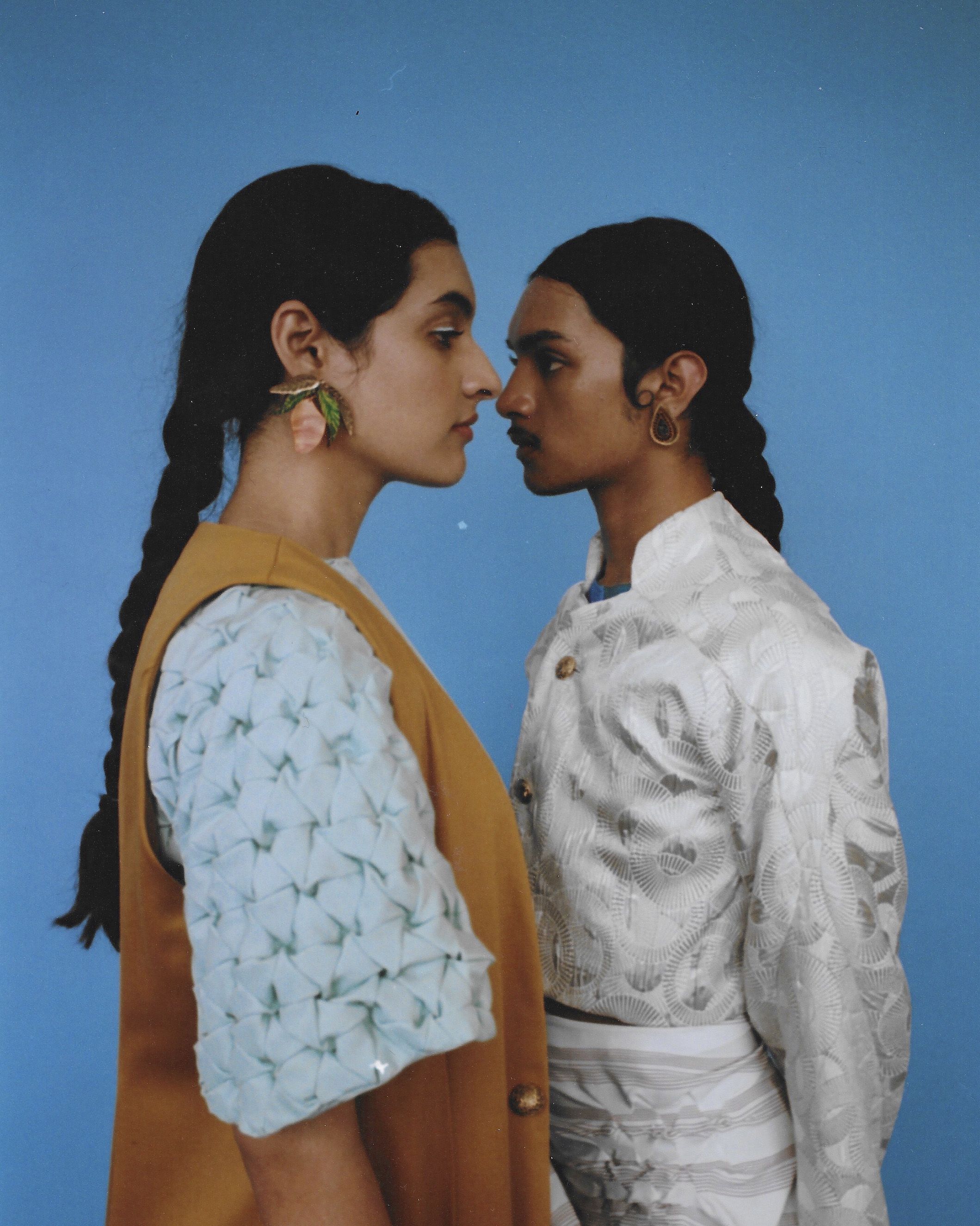 Two models standing face to face against a blue background