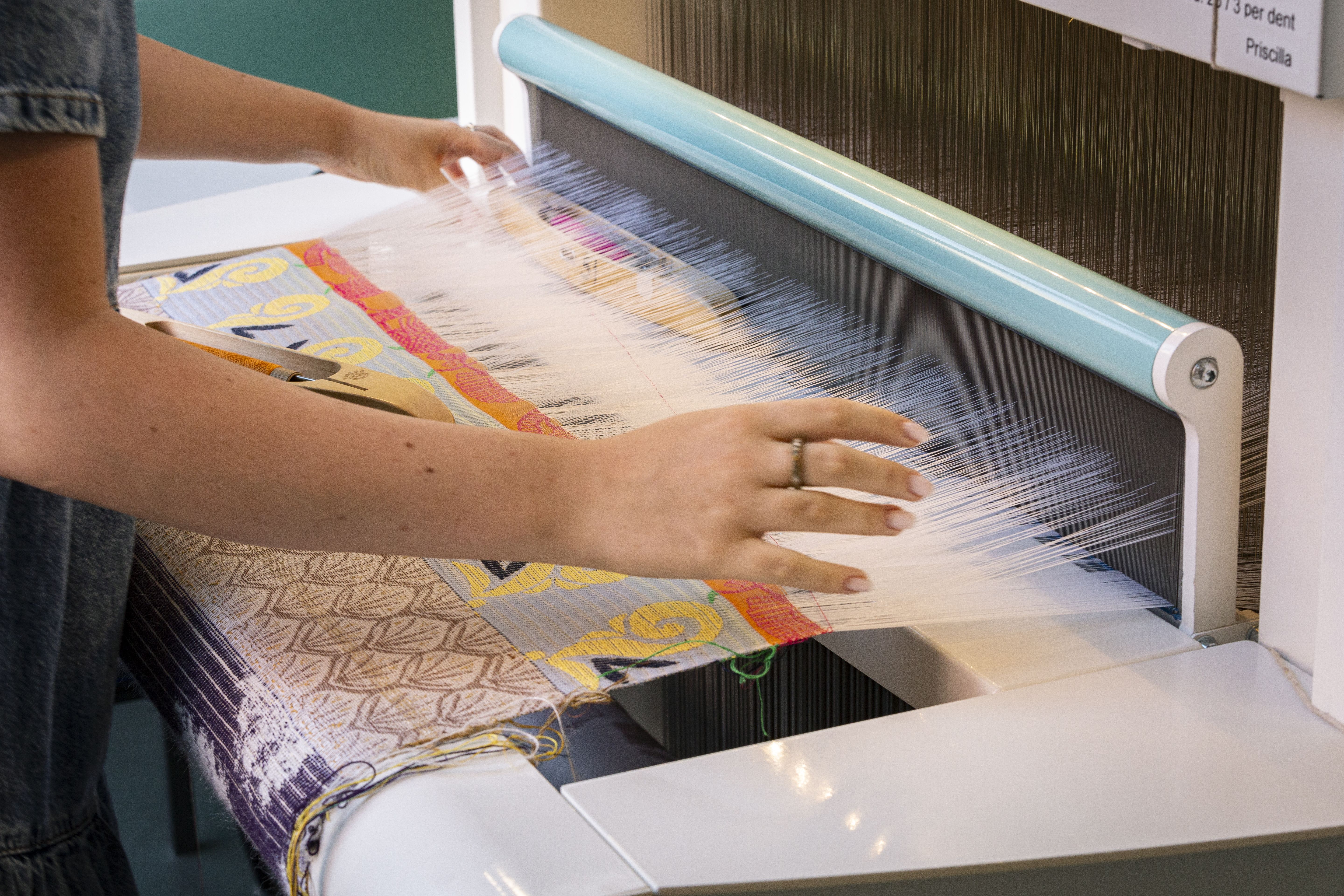a fair of hands working on a weaving 