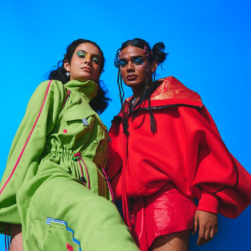 Two models in green and red outfits looking at camera