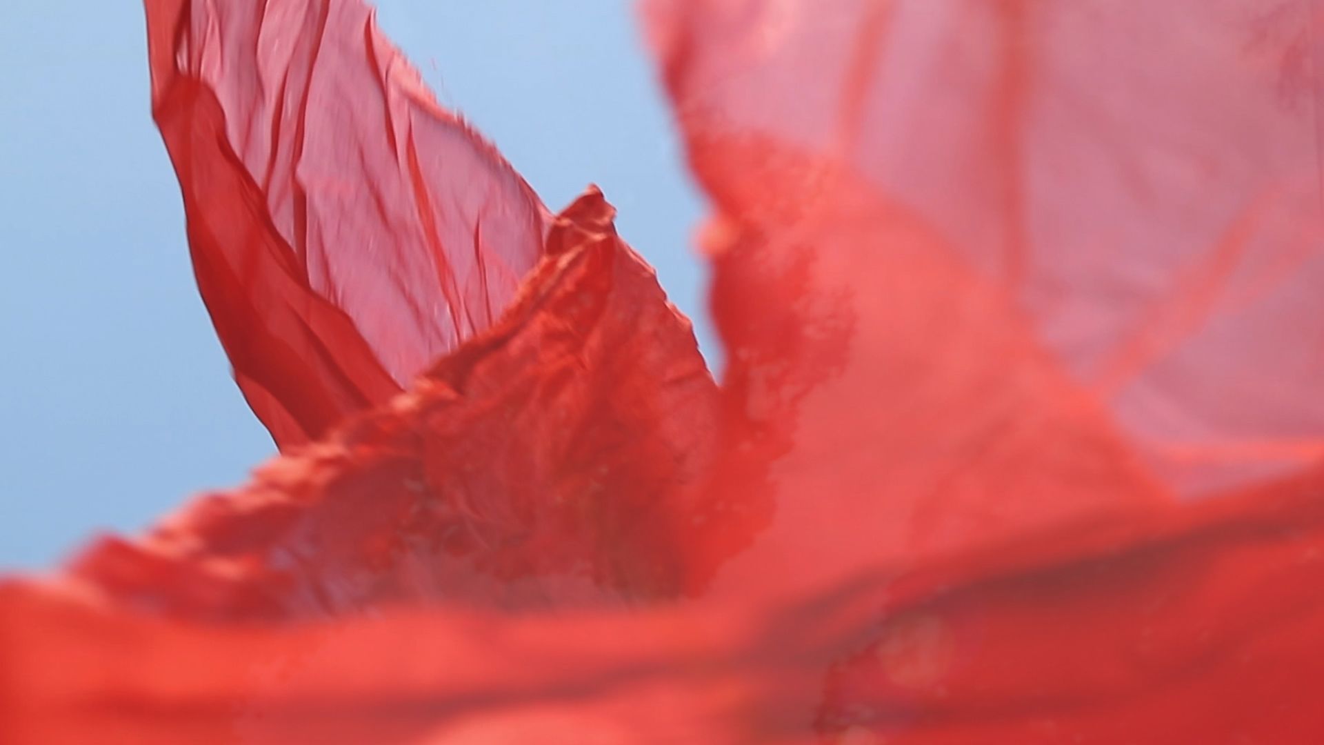 A red see through material floating against a blue sky