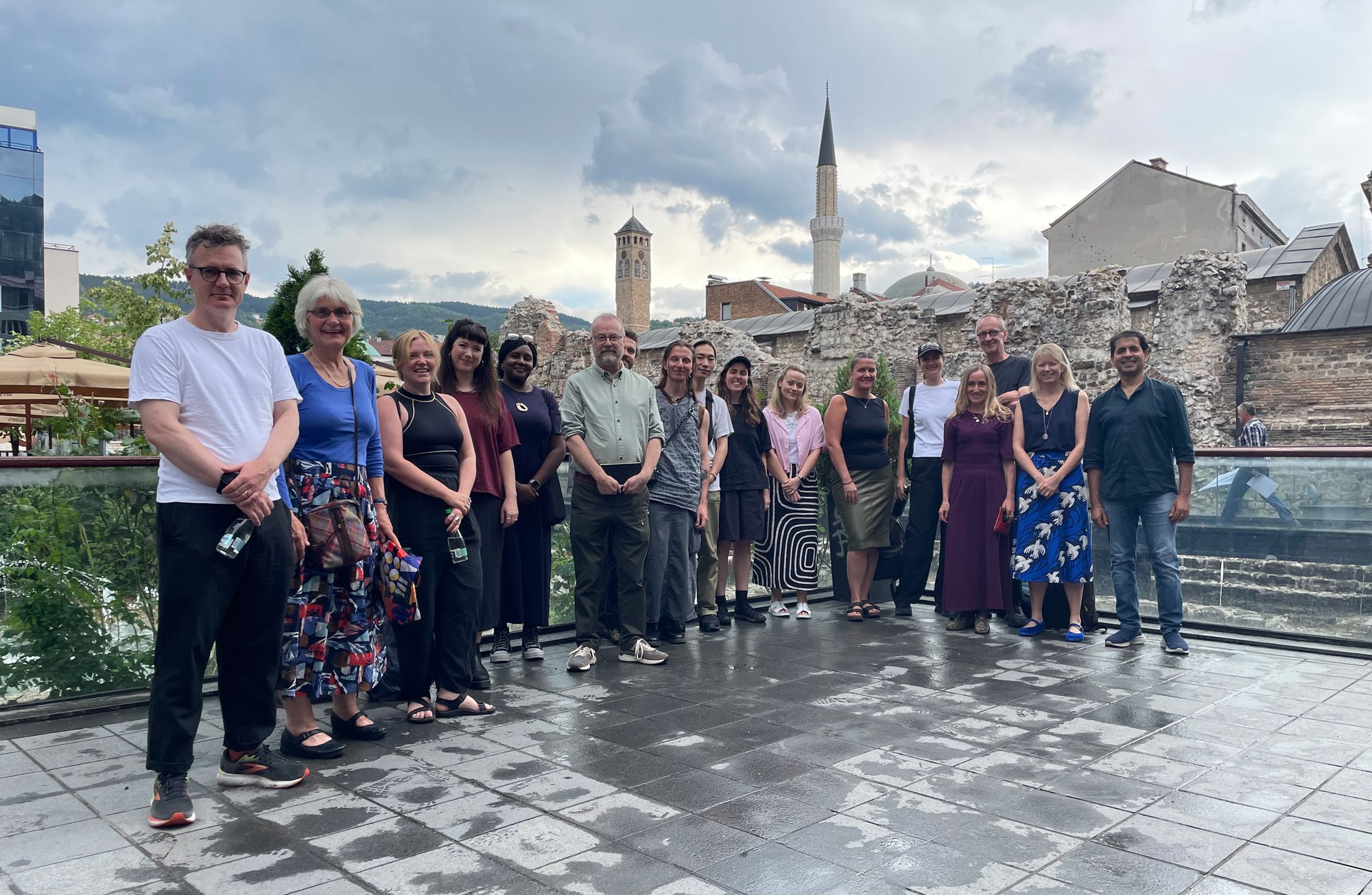 A group photo of men and women posed smiling for the camera in front of a city scene