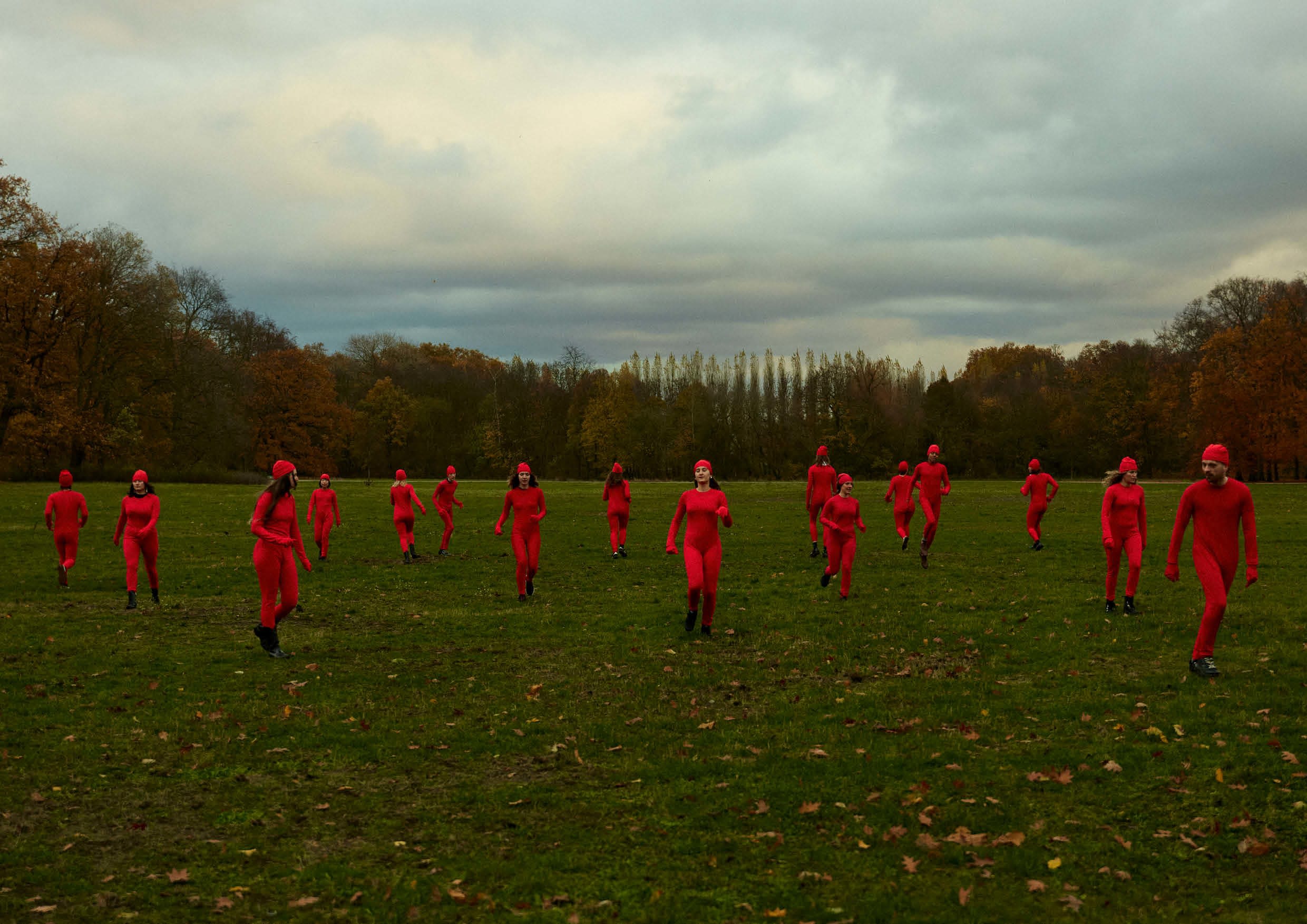 An image of multiple people wearing all read in a green field of grass