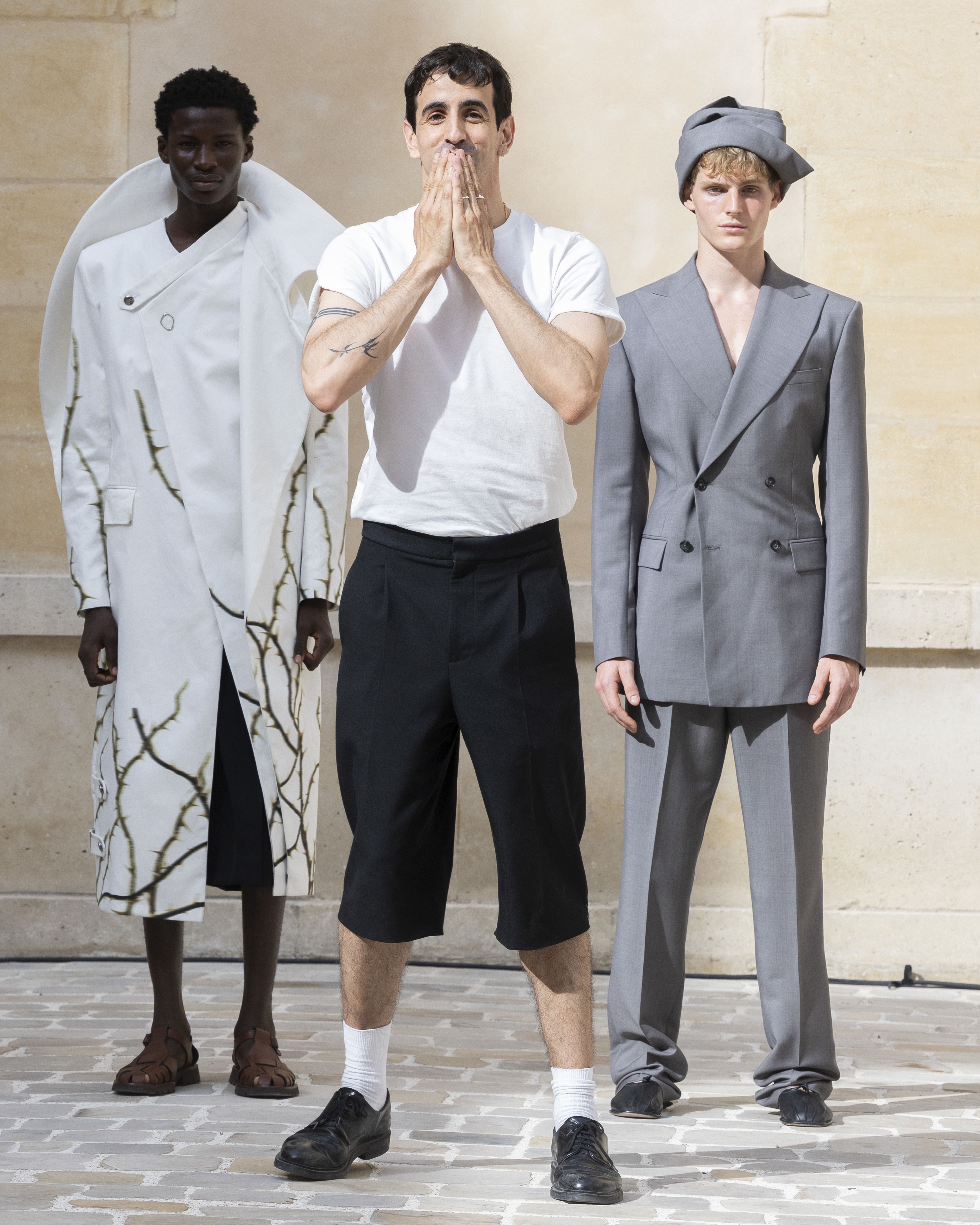 Man standing in front of two runway models taking a bow at the end of the show.