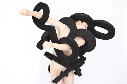 A woman moves with black shapes on her
