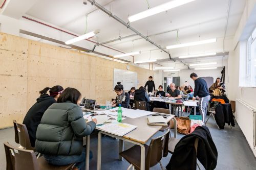 Students working at a desk inside Central Saint Martins' Archway campus
