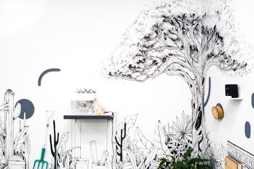 Wall installation showing a tree and garden equipment drawn onto the wall in black marker pen.