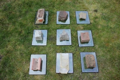 bricks and rocks laying on glass sheets on grass
