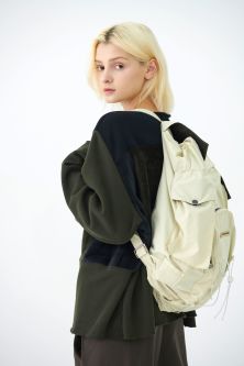 Female model in black sweater wearing a cream backpack