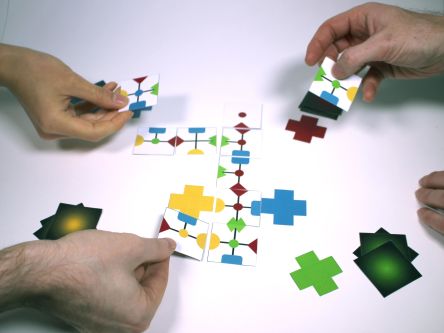 image of three hands playing game holding the pieces in their hands