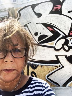 Tutor, Dominique L’Olive, stood in front of graffiti.