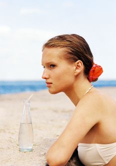 Woman resting her arms on a rock with a glass bottle of water in front of her