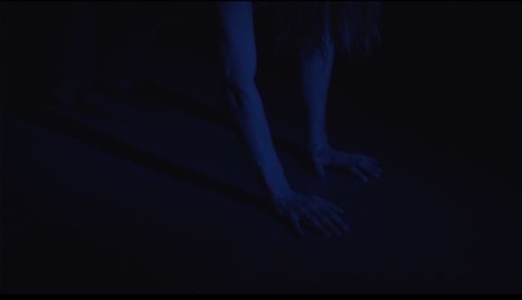A dark blue image shows a pair of hands on the floor