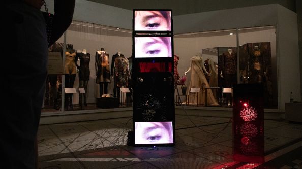 Three screens stacked on top of each other play films of a woman's eyes.