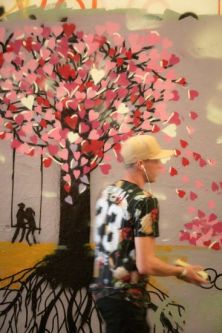 blurred figure in front of tree artwork on wall