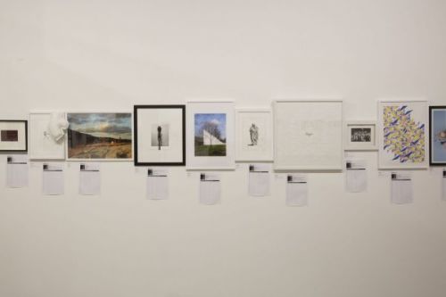 Installation photograph of various artworks hung on the wall in the silent auction