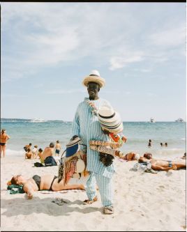 Man on a beach in a straw hat selling gifts. UAL Study Abroad Photography 