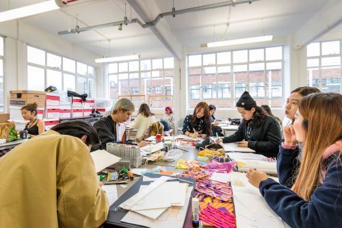 Students working at a desk inside Central Saint Martins' Archway campus