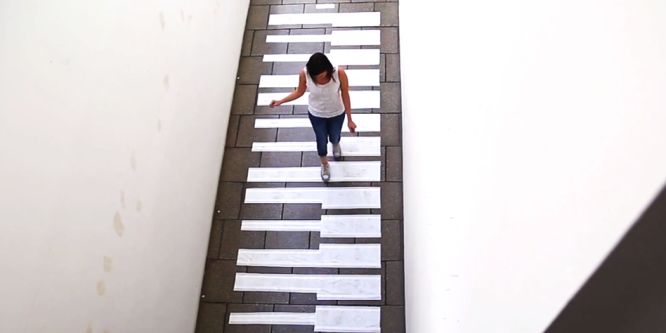 A lady walks across a melody piano down a corridor