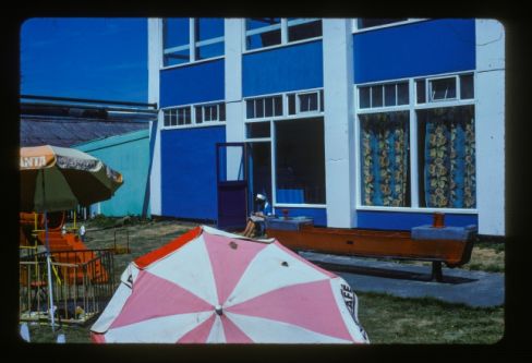 Vintage photograph of a seaside umbrella in front of a hotel.