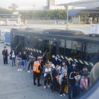 people wearing masks queuing for airport shuttle bus