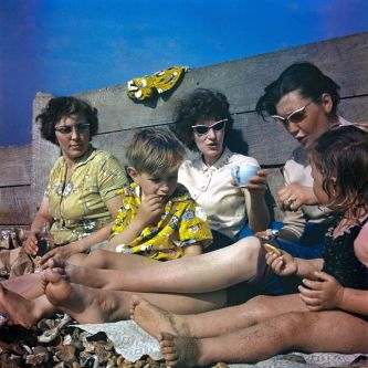 Photo of a family sitting together on the sea front.