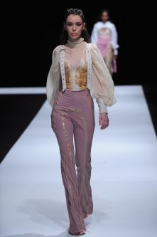Female model wearing pink trousers and creamy blouse designed by Molly Lockley