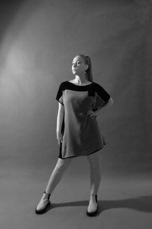 Model in black shirt dress posing with back to the camera in black and white backdrop