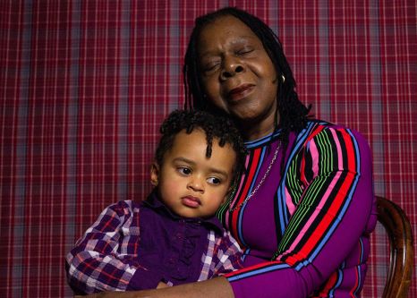 Image depicts a grandmother holding her grandchild.