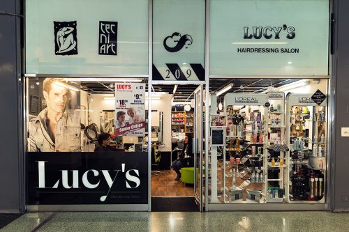 Lucy’s Hairdressing Salon, in the Elephant and Castle shopping centre since 1992, and the new logo on the window display designed by Francisco Casaroti.